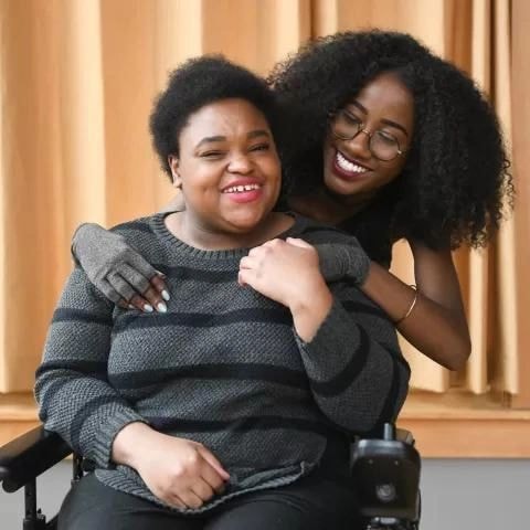 Two women smiling and embracing indoors